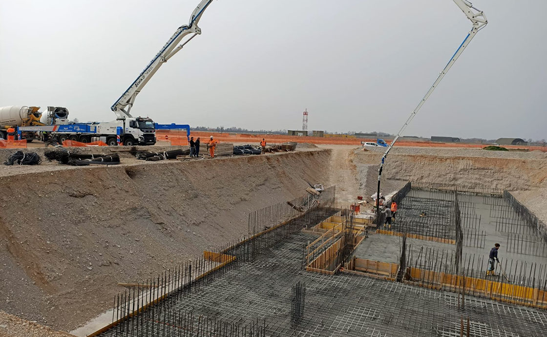 Cantiere con operai per realizzazione di hangar di manutenzione, linee di volo, polo tecnologico, centrali elettriche