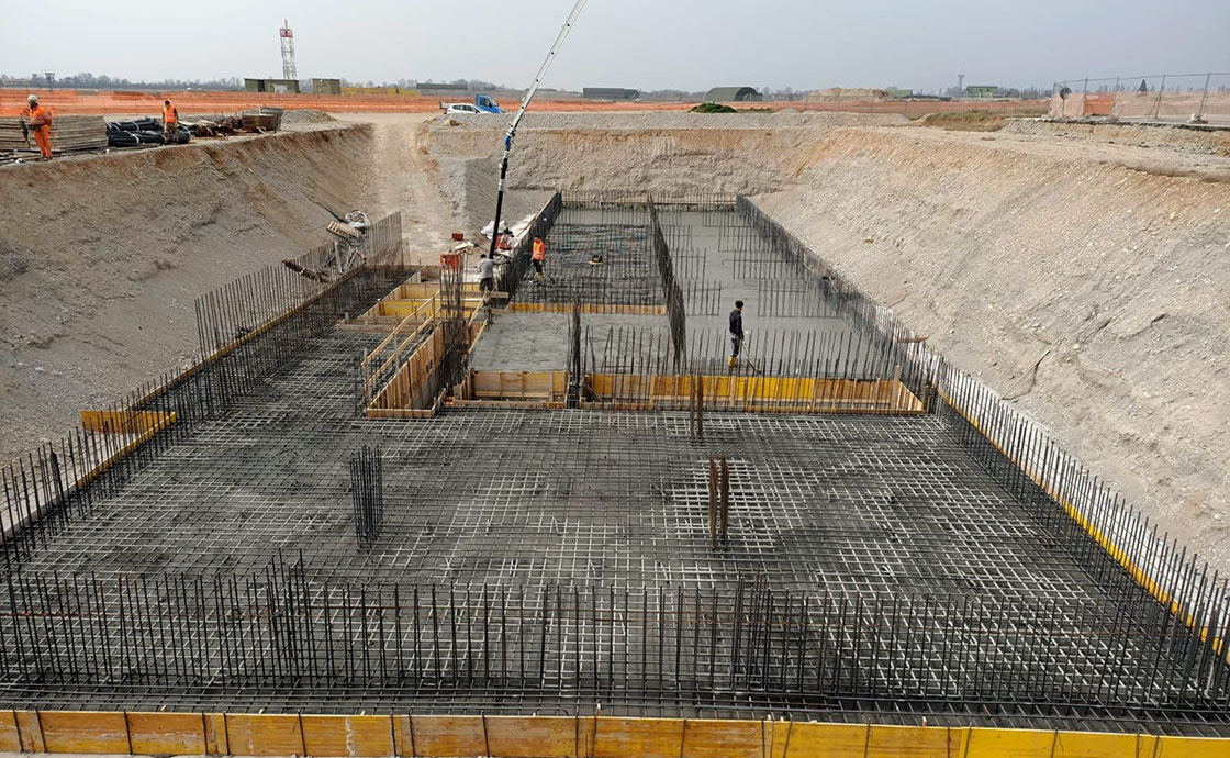 Cantiere con operai per realizzazione di hangar di manutenzione, linee di volo, polo tecnologico, centrali elettriche