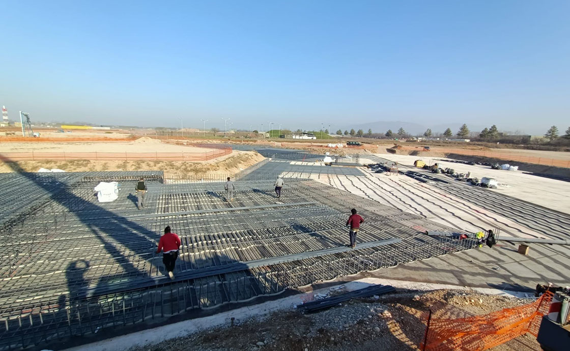 Cantiere con operai per realizzazione di hangar di manutenzione, linee di volo, polo tecnologico, centrali elettriche