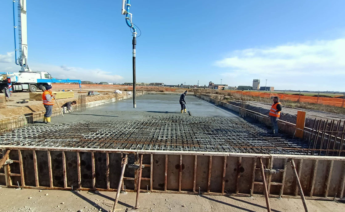 Cantiere con operai per realizzazione di hangar di manutenzione, linee di volo, polo tecnologico, centrali elettriche